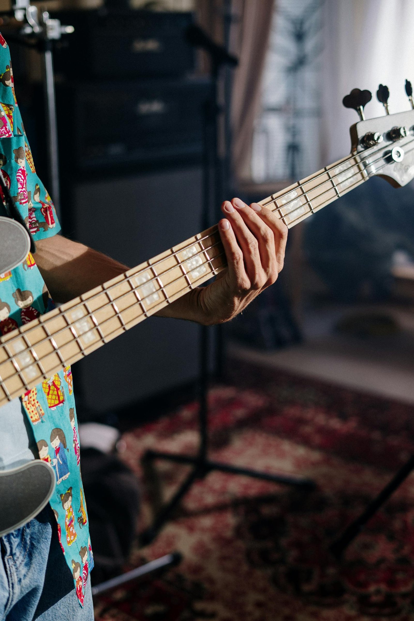 Close-up of a musician playing bass guitar in a cozy home studio.